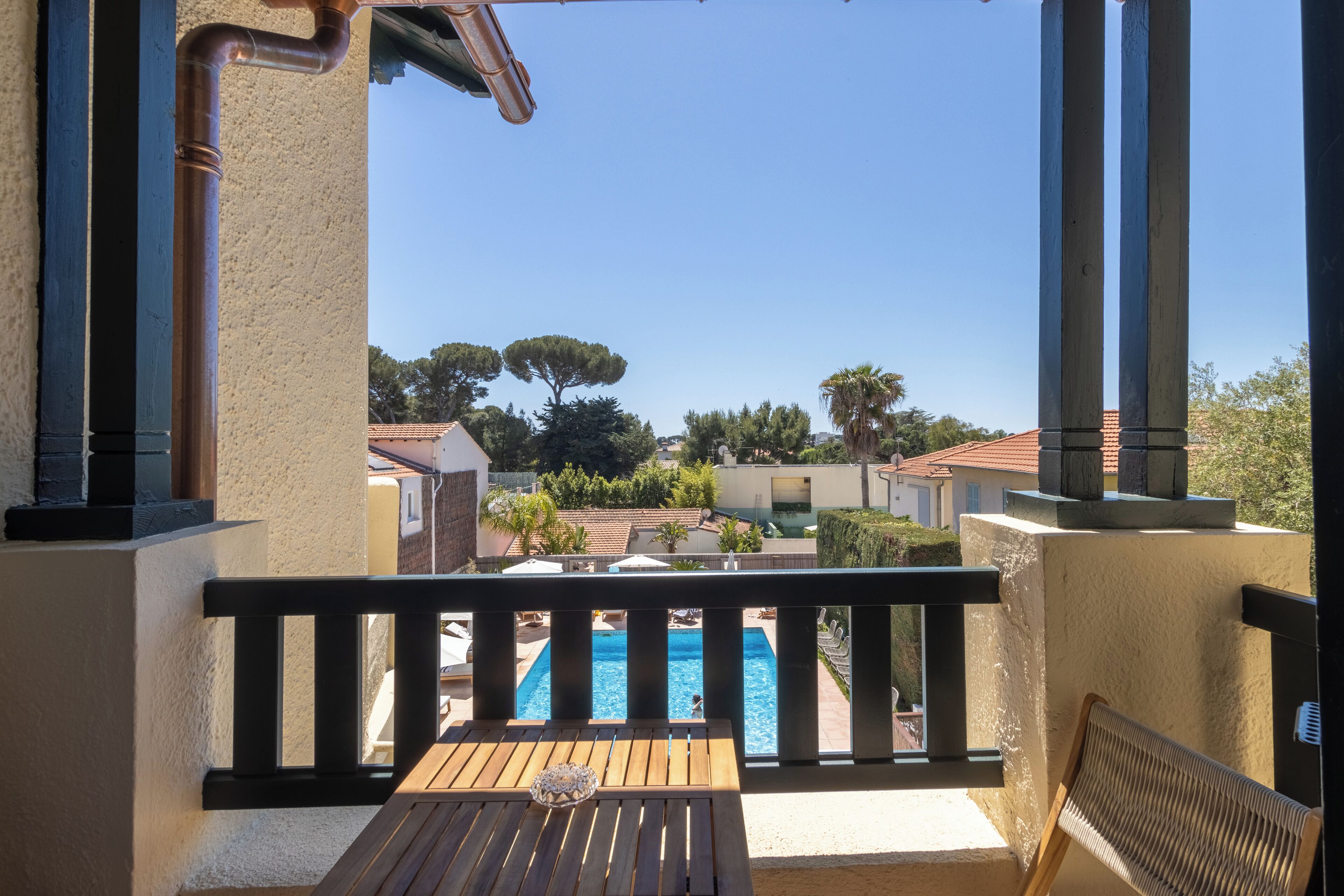 Un balcon donnant sur une piscine, une table en bois et une chaise.