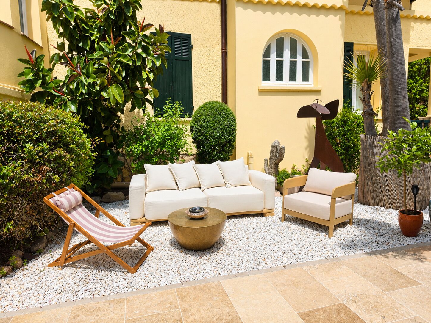 A patio with a white sofa, two armchairs, a small table, and a striped lounge chair.