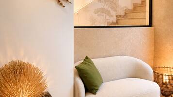 A modern interior with a sofa, a decorative wall piece, and a staircase with a skylight.