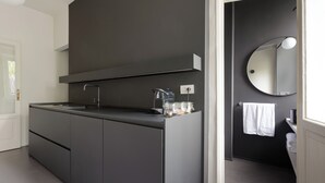A modern bathroom with a dark gray vanity, a round mirror, and a white towel hanging on the wall. - Brera Apartments in Porta Volta (Milan)
