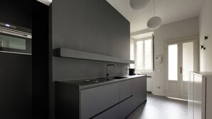 A modern kitchen with a large island, built-in oven, and a pendant light. - Brera Apartments in Porta Volta (Milan)