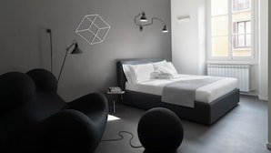 A modern bedroom with a bed, two bedside lamps, a geometric wall decoration, and a small table with a book. - Brera Apartments in Porta Volta (Milan)