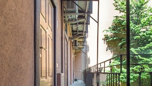A narrow balcony with a metal railing, a brown doormat, and a view of a tree. - Brera Apartments in Porta Volta (Milan)