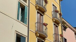 Un immeuble à plusieurs étages, doté de balcons, de portes en arc de cercle et surplombant un ciel d’un bleu éclatant.