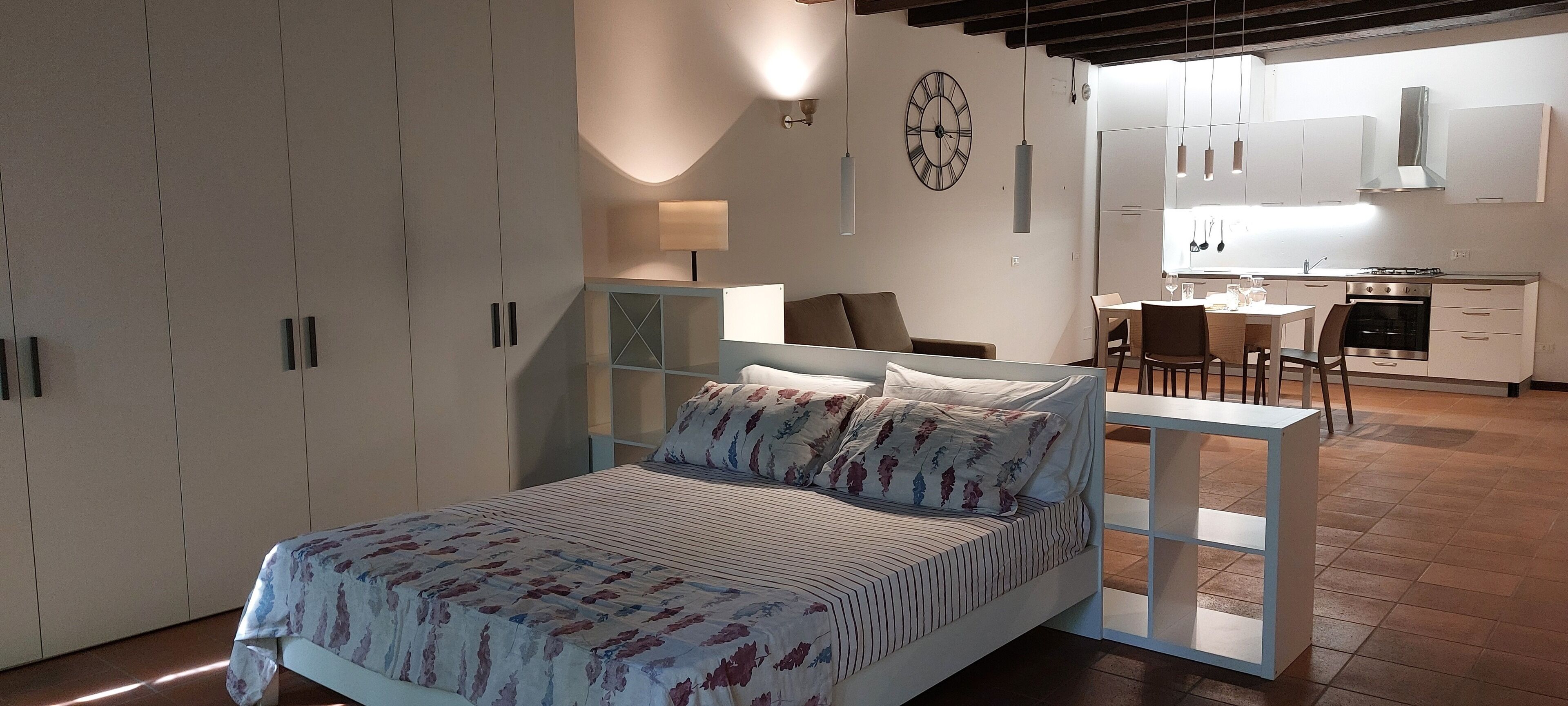 Una camera da letto con un letto, una scrivania e angolo cottura.