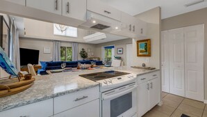 A modern kitchen with white cabinetry, a built-in stove, and a large island with a granite countertop.