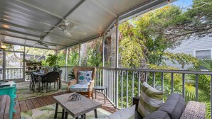 A covered outdoor patio with a table, chairs, and a sofa.