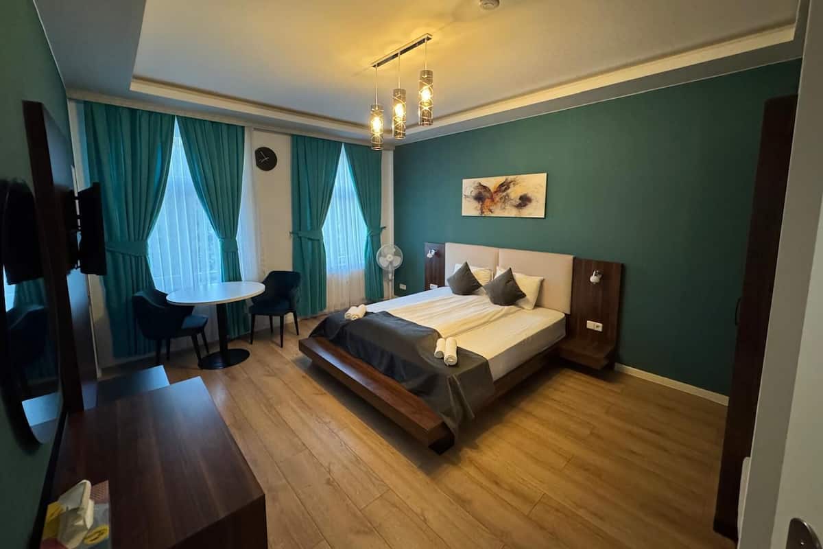 A modern hotel room with a bed, a desk, and a chair.