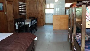 Una habitación acogedora en el ático con cama, literas, una mesa de comedor y una zona de cocina.