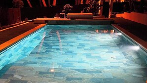 A swimming pool with a stone tile floor and an orange border.