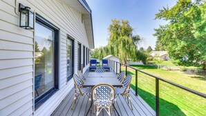 Une terrasse avec une table et des chaises, une rambarde et une vue sur une pelouse verdoyante et des arbres.