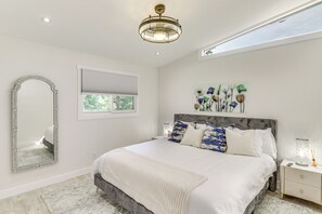 Ein Schlafzimmer mit einem großen Bett, einem Spiegel, einem Fenster und einer Deckenleuchte.
