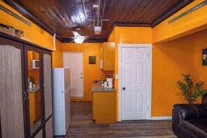 Compact kitchen area with a refrigerator, microwave, and coffee maker, adjacent to a cozy living space.