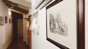 Un couloir avec des œuvres d’art encadrées accrochées aux murs, une porte en bois et un radiateur.