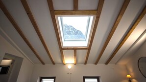 Una habitación con tragaluces, vigas de madera y vistas a la montaña.