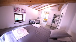 Un dormitorio con una cama, un ventanal, una litera y una mesita.