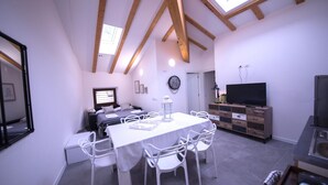 A compact living space with a dining area, a TV, and a kitchenette.