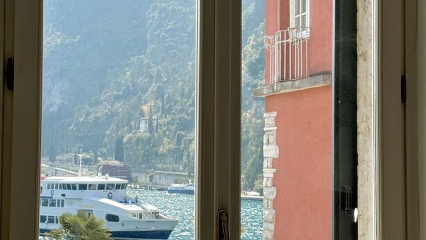 A view through a window of a boat docked near a building with a red facade and stone columns.