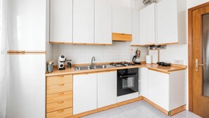 Eine moderne Küche mit weißen Schränken, Holzarbeitsplatten, einem Gasherd und einem eingebauten Backofen.