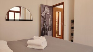 A bedroom with a bed, a mirror, a door, and a wall-mounted artwork. - One Bedroom Apartment (Riva del Garda)