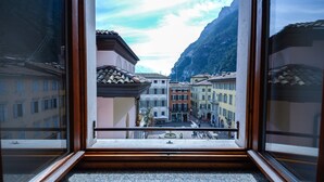 Une vue depuis une fenêtre donnant sur une rue bordée d’immeubles, avec une montagne en arrière-plan.