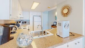 A modern kitchen with a granite countertop, stainless steel sink, and white cabinets.