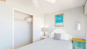 A bedroom with a bed, a nightstand, a wardrobe, a painting, and a mirror.