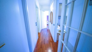 Un couloir étroit avec un plancher en bois et des murs blancs.