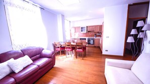 Una sala de estar con un sofá de cuero, una mesa de comedor con sillas y una cocina al fondo.