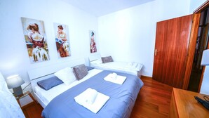 Una habitación de hotel con dos camas, un armario de madera y obras de arte en las paredes.