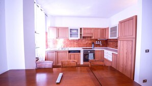Una cocina compacta con armarios de madera, lavavajillas y una mesa con sillas.