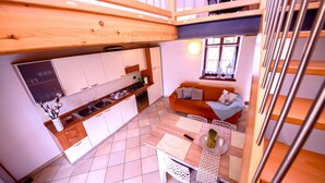 Una cocina compacta con gabinetes blancos, encimera de madera y un área de comedor con mesa y sillas.