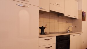 Een keuken met witte kastjes, een zwarte koffiezetapparaat en een RVS spoelbak.