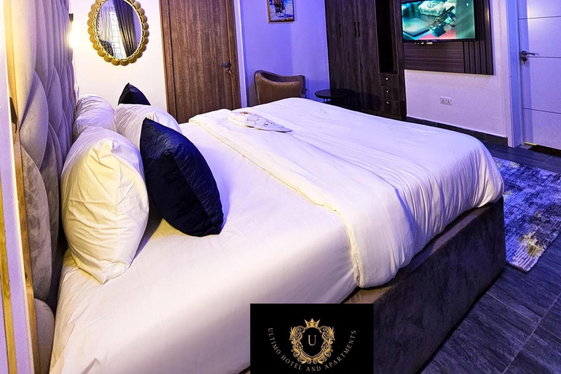 Un dormitorio de hotel con una cama grande, un televisor, un espejo y una puerta.