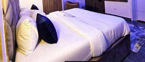 Un dormitorio de hotel con una cama grande, un televisor, un espejo y una puerta.