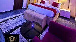 Un dormitorio moderno con cama, mesitas de noche, un espejo redondo y un sillón rojo.