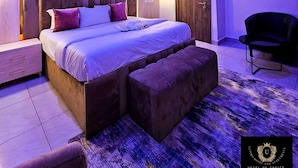 Une chambre moderne avec un grand lit, une tête de lit en bois et une table de chevet.