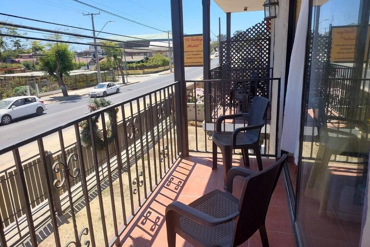 Ein Balkon mit zwei Stühlen, einer Brüstung und Blick auf eine Straße mit Autos.