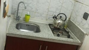 Une petite cuisine équipée d’un évier, d’une cuisinière à gaz et d’un distributeur de savon vert.