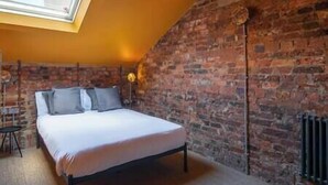 A bedroom with a bed, a brick wall, a radiator, and a skylight. - Terrace View · City Centre Modern Apartment (West Yorkshire)
