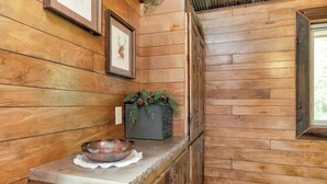 Ein Holzinterieur mit einer Steinarbeitsplatte, einem Bild von einem Reh und einem Pflanzgefäß mit Tannenzapfen.