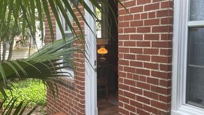 Un edificio de ladrillo con una puerta, una ventana y un felpudo.