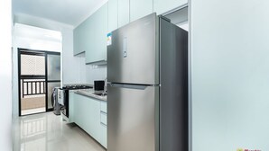 Une cuisine moderne dotée d’appareils électroménagers en acier inoxydable, de meubles de couleur bleu clair et donnant sur un balcon.