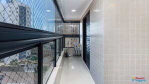 Un couloir avec une rambarde en verre, une serpillière et un seau à serpillière, qui mène à une porte dotée d’une fenêtre.