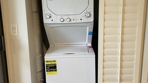 Eine Waschmaschine und ein Trockner in einem Gerät, mit ENERGY GUIDE-Aufkleber, in einem Waschraum mit Tür.