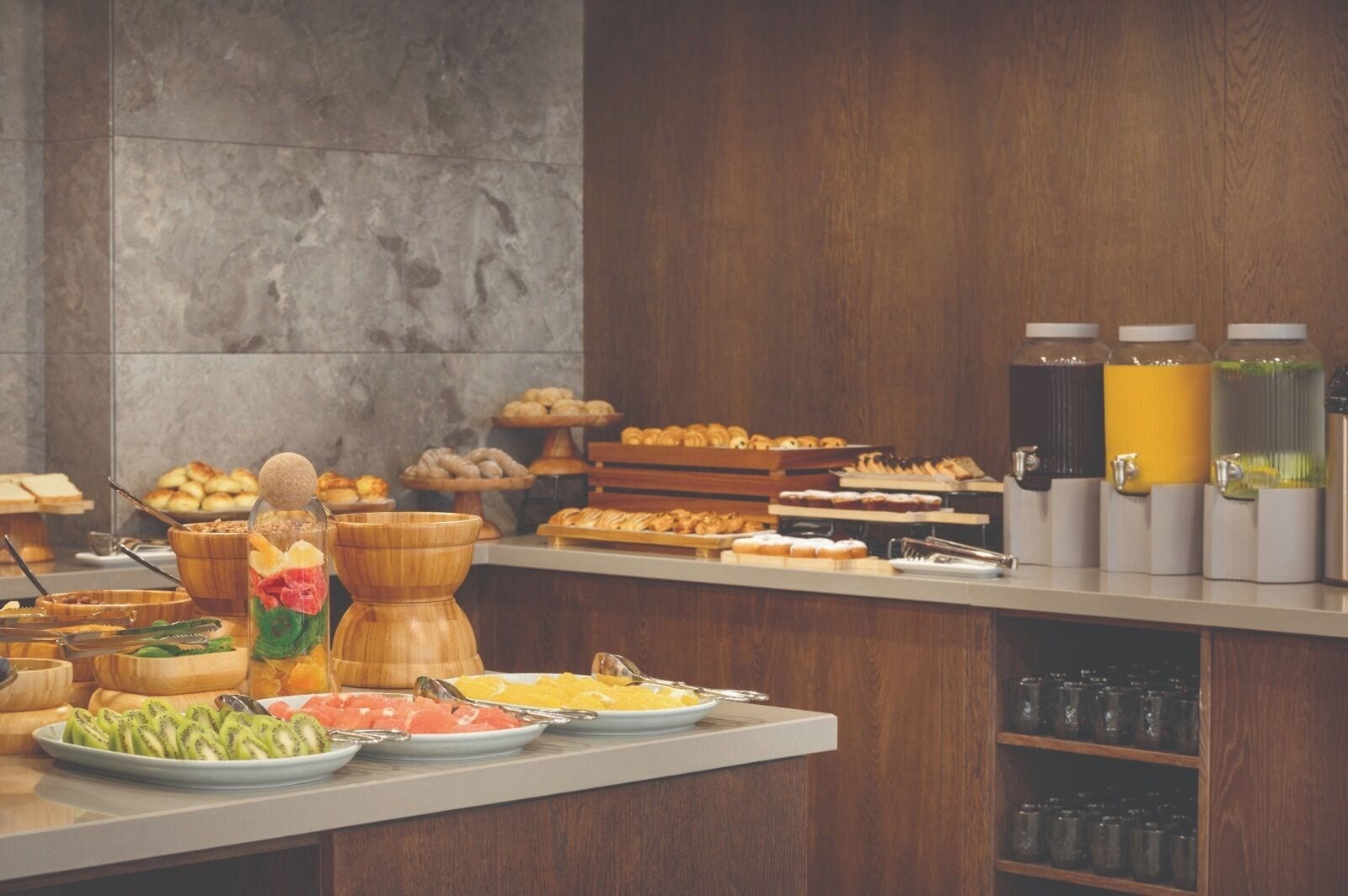 A buffet with various food items, including fruits, pastries, and beverages.