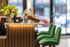 A reception desk with a wooden finish, a vase of yellow flowers, a basket of fruits, and a bottle of water. - Rainbow Residence Batumi (Batumi)