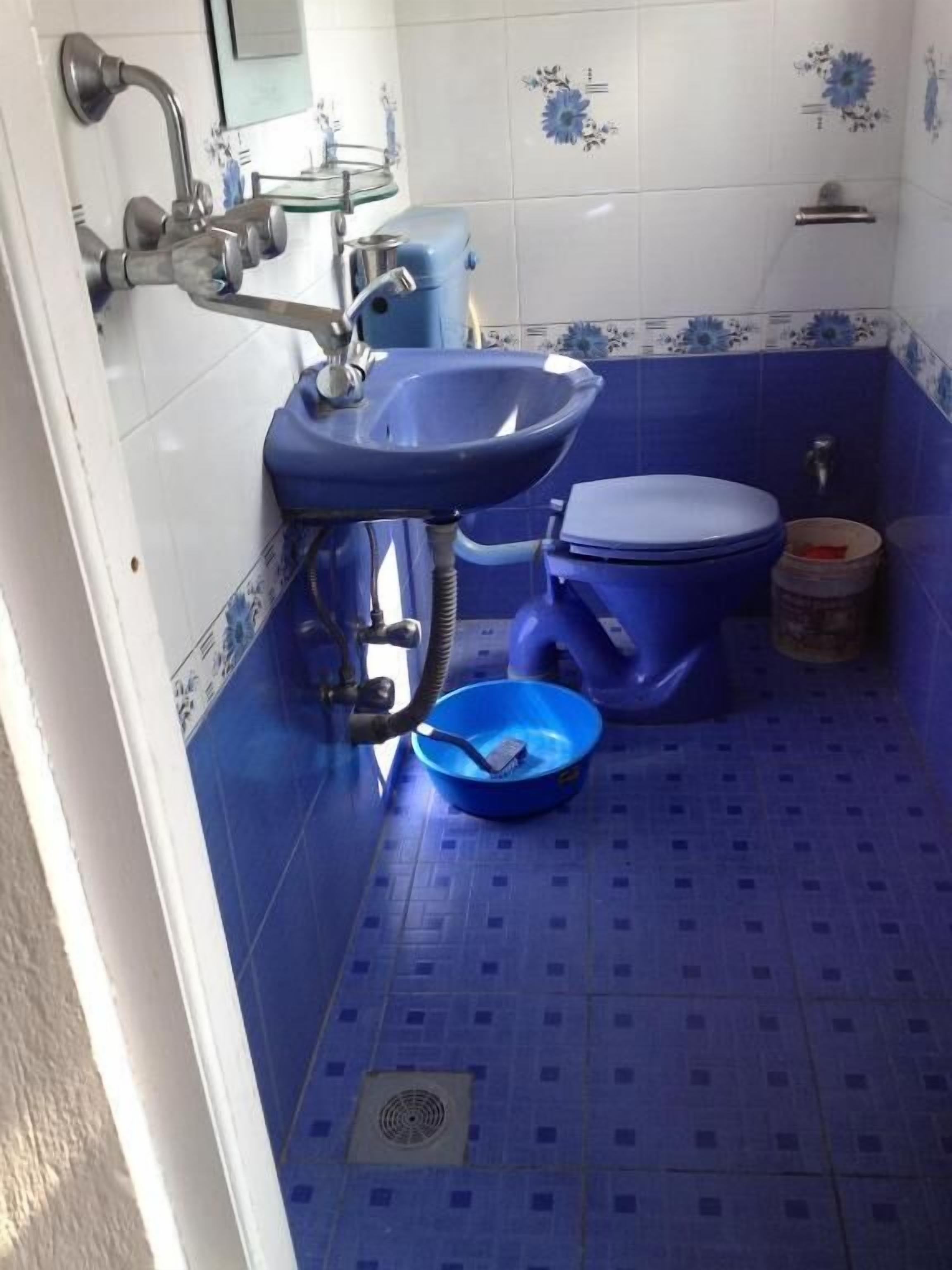 Ein Badezimmer mit blauem Waschbecken, Toilette und blau gefliestem Boden.