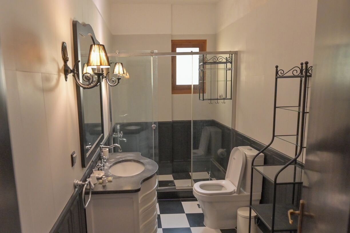 Une salle de bain avec un carrelage noir et blanc à motifs géométriques, un lavabo avec un miroir, des toilettes et un espace douche.
