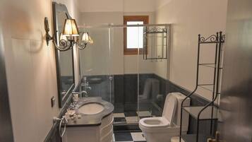 A bathroom with a black and white checkered floor, a sink with a mirror, a toilet, and a shower area.
